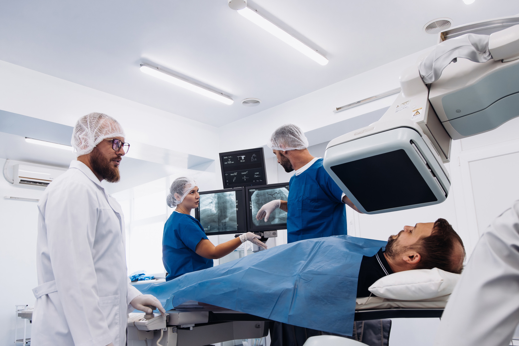Interventional radiology care team in a fluoroscopy suite preparing for a catheter-based procedure